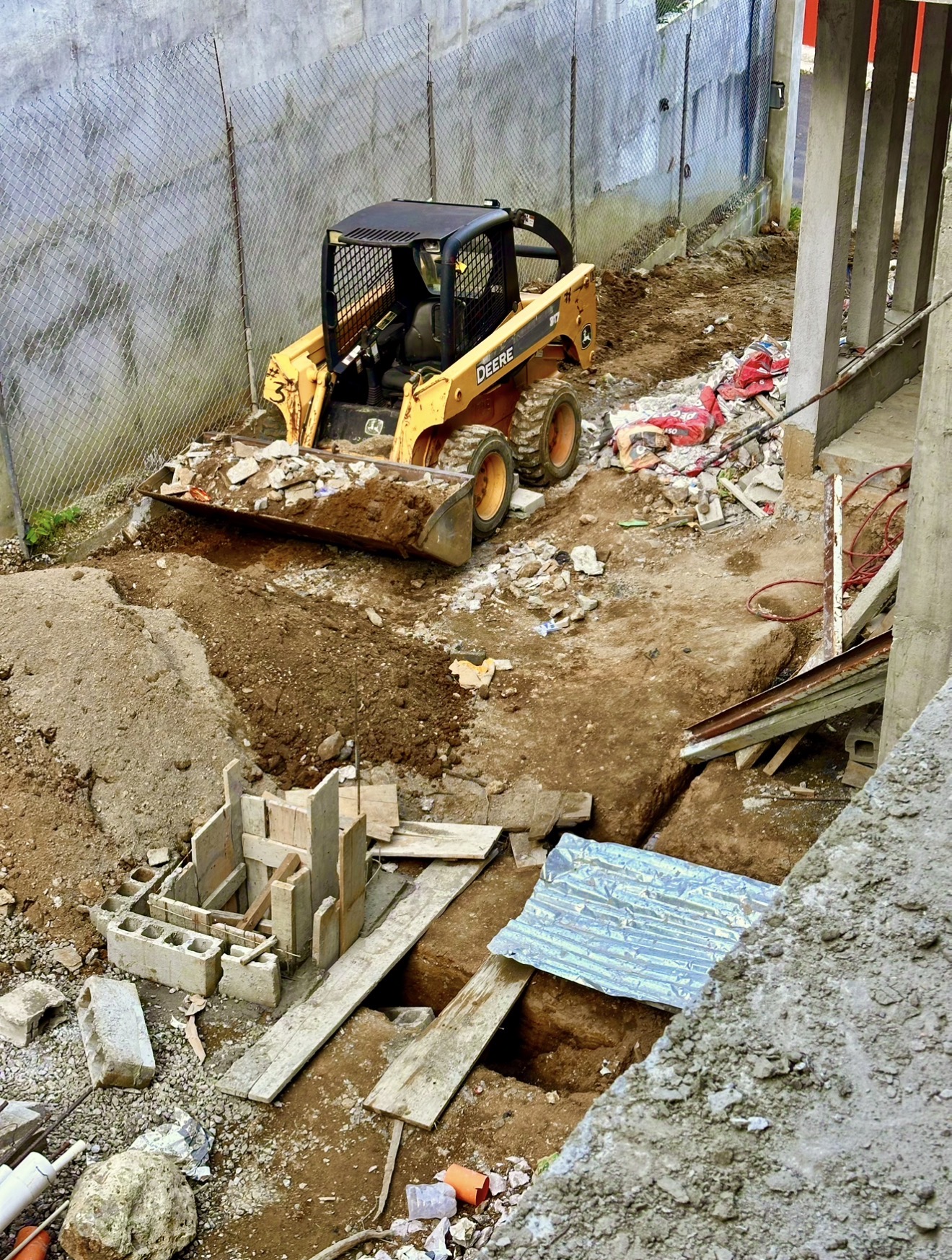 Minicargador amarillo trabajando con tierra y escombros en un área de construcción