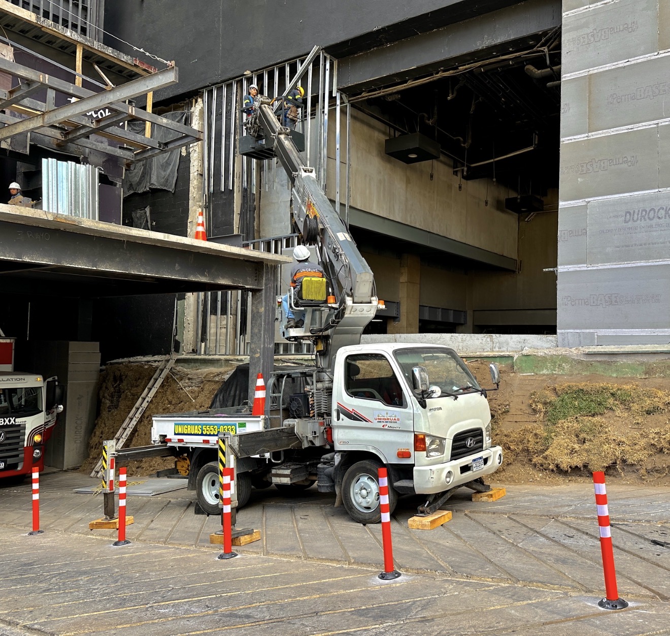 Personal en una canasta de UNIGRUAS realizando trabajos en altura en una fachada en construcción