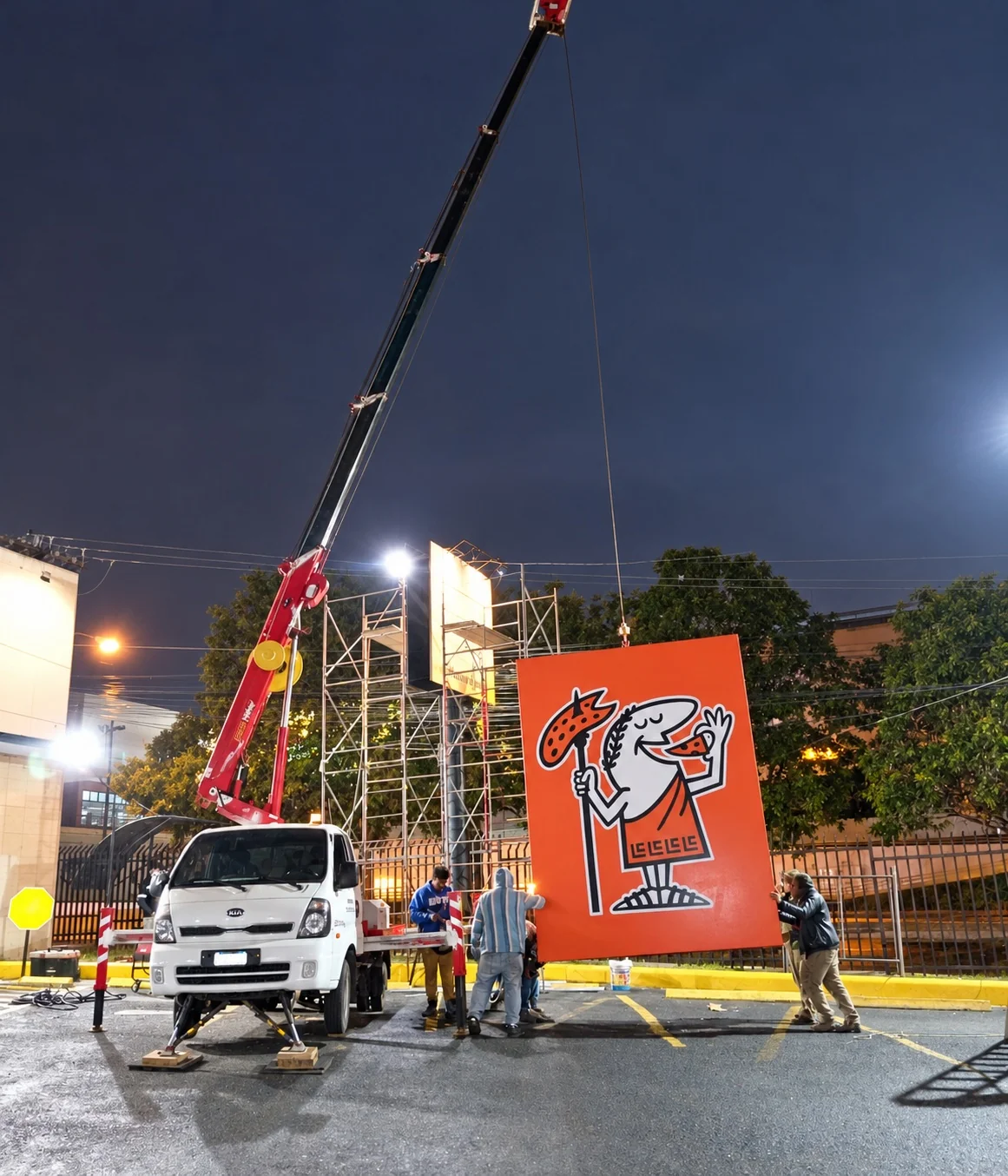 Grúas en la instalación nocturna de un elemento comercial